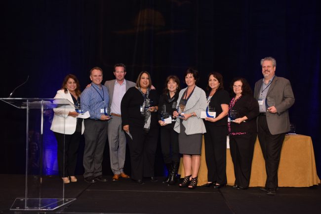 Award winners posing on stage with their trophies